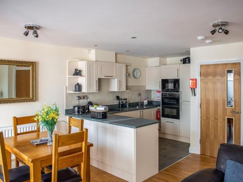 a kitchen with white cabinets and a table and a dining room at The Old Laundry 3 in Keswick