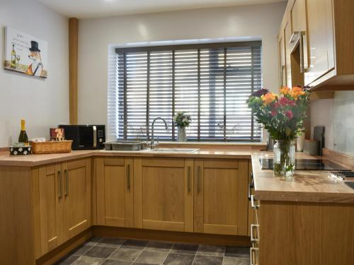 a kitchen with wooden cabinets and a sink and a window at Meadow View Cottage in Stanhope