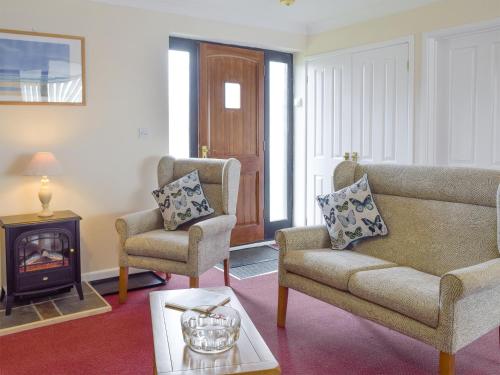 a living room with a couch and two chairs and a wood stove at Carol's Cottage - E3043 in Blyford