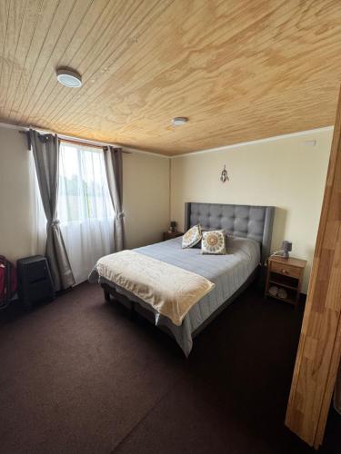 a bedroom with a bed and a wooden ceiling at Cabañas Campo Frutillar in Frutillar