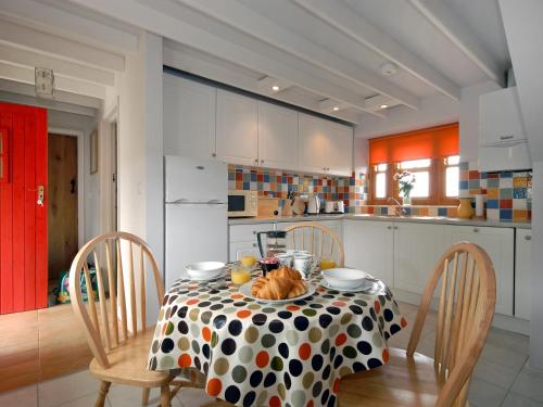 een keuken met een tafel met een polka dot tafelkleed bij Ria's Cottage in Landshipping