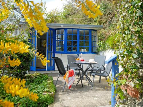 eine Terrasse mit einem Tisch und Stühlen vor einem blauen Haus in der Unterkunft Crows Cottage in Fishguard