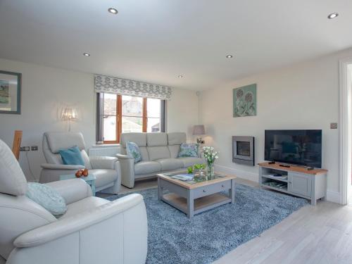 a living room with white furniture and a tv at The Linhay in Durleigh