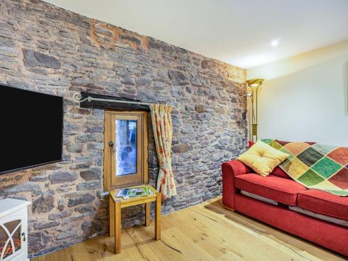 - un salon avec un canapé rouge et un mur en pierre dans l'établissement Horsecroft - Uk37462, à Dorstone