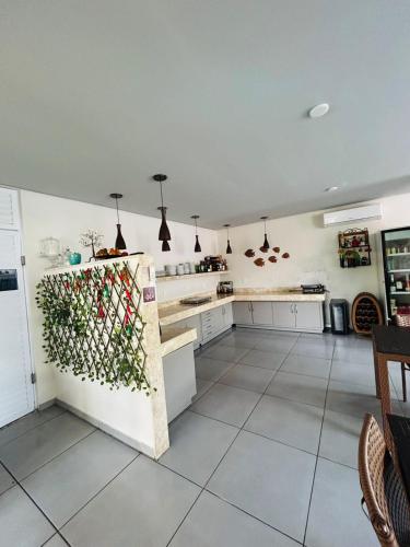 a large kitchen with white cabinets and a refrigerator at Chalé Murici Lençóis in Santo Amaro