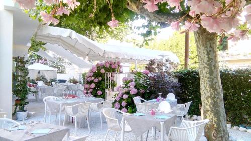 a group of tables with white chairs and pink flowers at Petit Hotel in Lido di Camaiore