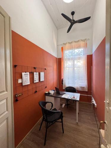 Bee Hostel في ليماسول: مكتب به مكتب وكرسيين ومروحة سقف