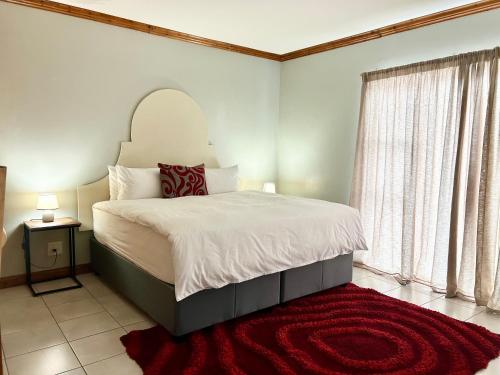 a bedroom with a large bed and a red rug at Colline Sainté Cottage in Port Alfred