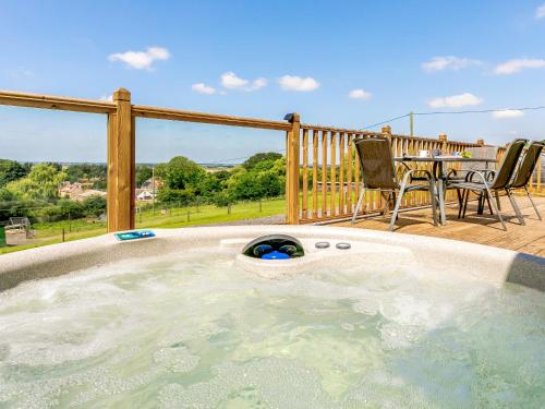 a hot tub on a deck with a table and chairs at Hill Crest Lodge 1 in Hemswell