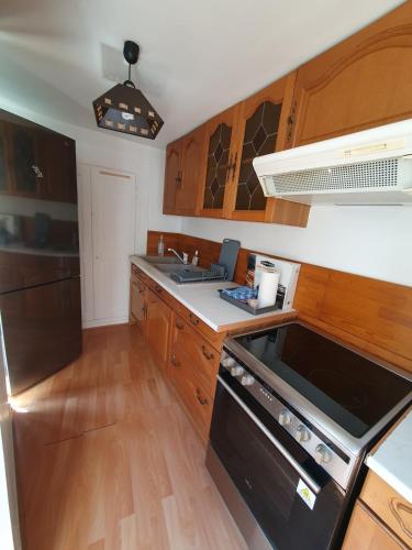 Duplex St Martin في أوسيل: مطبخ بخزائن خشبية وفرن أسود اللون.