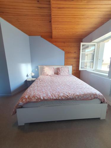 Duplex St Martin في أوسيل: غرفة نوم بها سرير وسقف خشبي