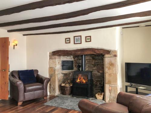 a living room with a stone fireplace and a tv at Church View Cottage & Barn in Hatherleigh