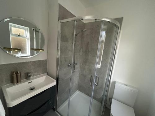 ein Badezimmer mit Dusche, Waschbecken und Spiegel in der Unterkunft Westport Coastal Cottage in Westport