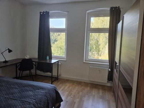 a bedroom with a bed and a desk and two windows at Große, moderne, helle Unterkunft mit Essküche all-in LTE in Gera