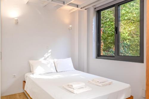 a white bedroom with a bed with two towels on it at Central cozy garden flat in Mesochórion