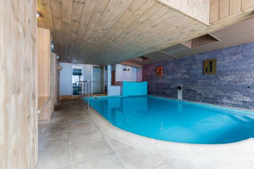 - une grande piscine dans un bâtiment doté d'un plafond en bois dans l'établissement Alp'Hotel, à La Clusaz