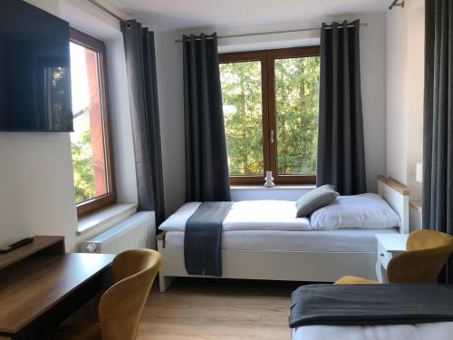 a bedroom with two beds and two windows at Pension Zollhaus in Oy-Mittelberg