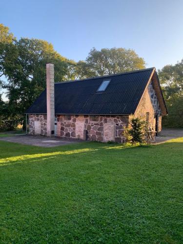 an old stone building with a chimney and a grass field at Stone house with direct access to Haraldsted Lake in Ringsted
