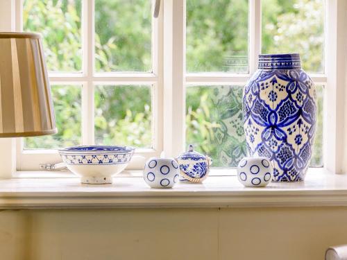a table with a blue and white vase on a window at Coach House - E5120 in West Burton
