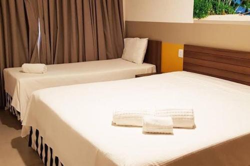 two beds in a hotel room with white sheets at Enjoy olimpia park resort in Olímpia