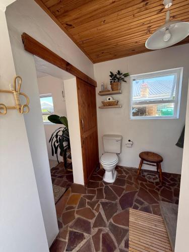 a bathroom with a toilet and a wooden ceiling at Seaside Garden Cottage Schoenmakerskop in Gqeberha