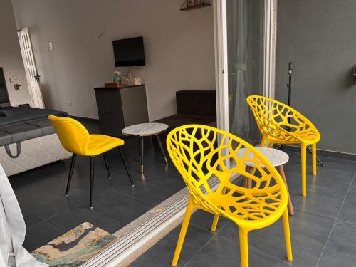 a living room with yellow chairs and a table at Casa Oceanus - Sea Facing Forest View Room - Ganpatipule in Nevra