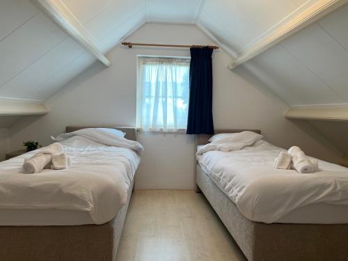 two beds in a room with a window at het Veenhuus in Nieuwlande