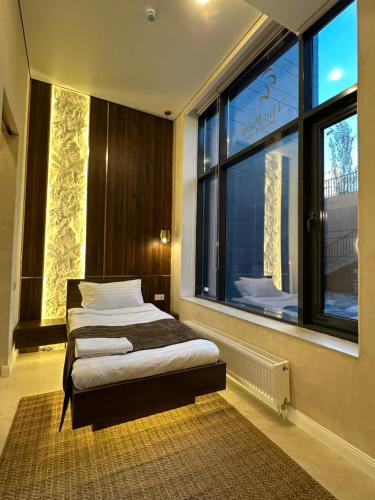 a bedroom with a bed and a large window at The Palm hotel & spa in Almaty