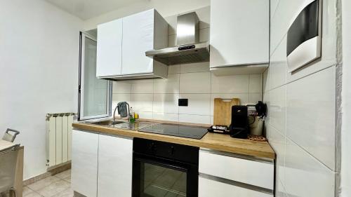 a kitchen with white cabinets and a sink and a stove at Fronte Mare Ampio Quadrilocale in Alassio