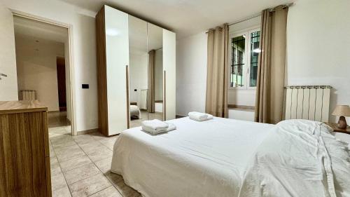 a bedroom with a white bed and a large mirror at Fronte Mare Ampio Quadrilocale in Alassio