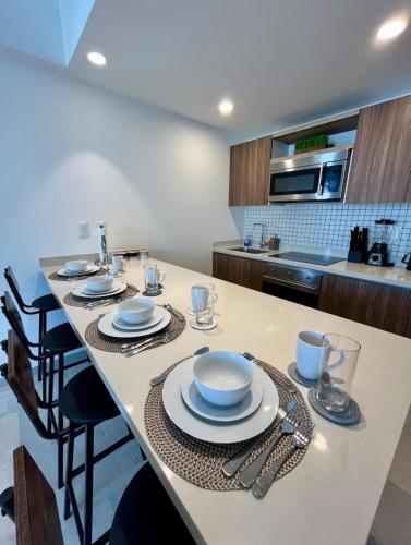 a kitchen with a table with plates and utensils at Casa Xaman-Ha At Urban Towers in Playa del Carmen
