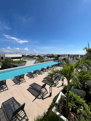 a pool on the roof of a building with chairs and trees at Casa Xaman-Ha At Urban Towers in Playa del Carmen