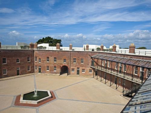 Un gran edificio de ladrillo con un patio delante. en The Sergeants Quarters, Golden Hill Fort, en Freshwater