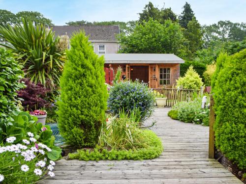 a garden with a wooden walkway in front of a house at Ty Lewis Cottage in Llanelli