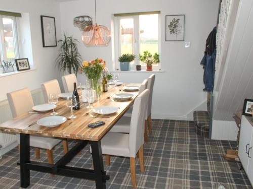 a dining room with a wooden table and white chairs at Hornby Cottage in Saint Michaels on Wyre