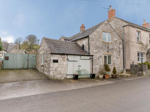 an old stone house with a garage on a street at The Smithy - E5445 in Brassington