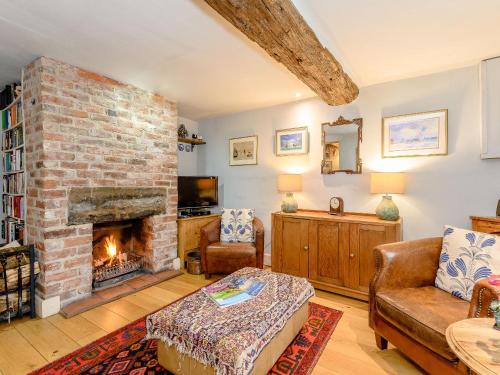 a living room with a brick fireplace and a couch at The Smithy - E5445 in Brassington