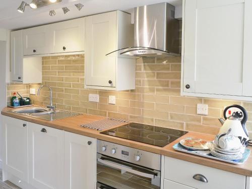 a kitchen with white cabinets and a stove top oven at Gwel An Porth in Charlestown