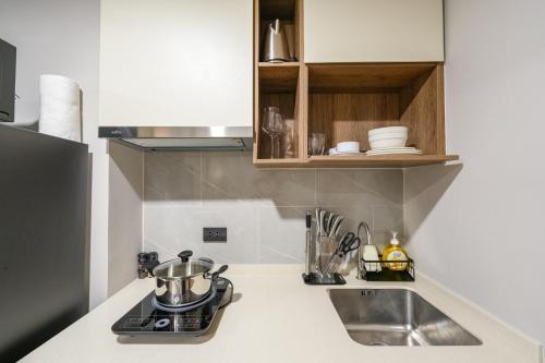 a kitchen counter with a sink and a stove at New Condo near Bangtao Beach - Space Cherngtalay in Ban Thalat Choeng Thale