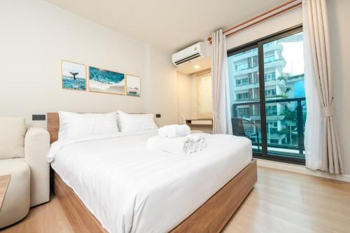 a white bedroom with a large bed and a window at New Condo near Bangtao Beach - Space Cherngtalay in Ban Thalat Choeng Thale