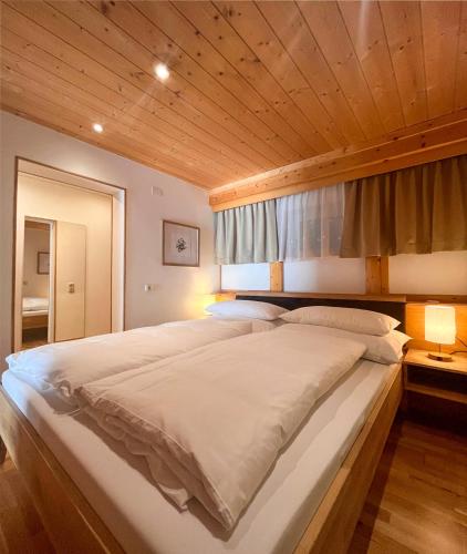a large bed in a bedroom with a wooden ceiling at Haus Bianca in Gaschurn