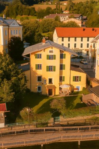 a yellow house on a hill next to some buildings at Villa Tegernsee - Exclusive Lakefront Villa with private Zirben Sauna, 4 Rooms for Family & Friends in Tegernsee