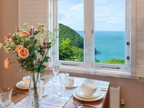 einen Tisch mit einer Vase aus Blumen und einem Fenster in der Unterkunft Haven Heights in Martinhoe