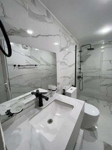 a white bathroom with a sink and a toilet at Wadi Rum Bubbles Luxury Camp in Wadi Rum