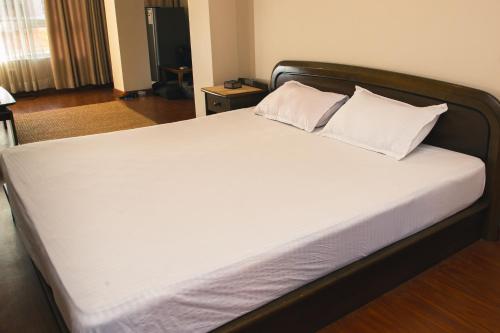 een bed met witte lakens en kussens in een kamer bij Thabahil Chhen in Kathmandu