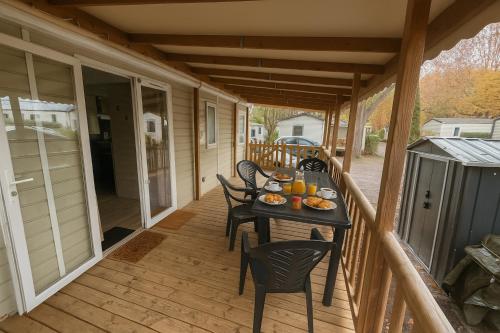 a porch with a table with food on it at Mobil-home 565 tout confort camping SIBLU 4 étoiles in Gastes