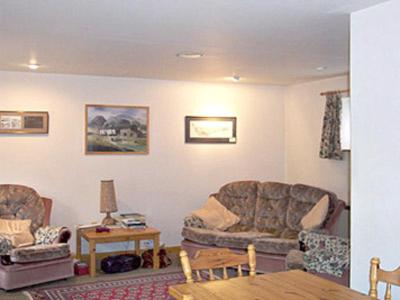 a living room with two chairs and a table at 2 Farfield Cottages in Sedbergh