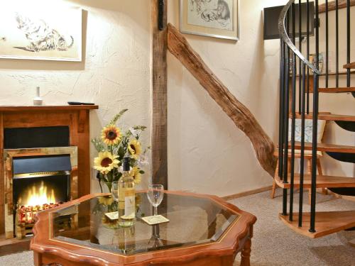 a living room with a fireplace and a glass table at Byre Cottage - 29410 in Elmsted