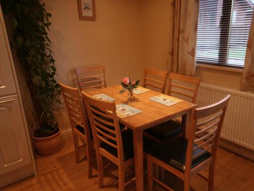a wooden table with chairs and a vase of flowers on it at Woodpeckers Cabin in Bridlington