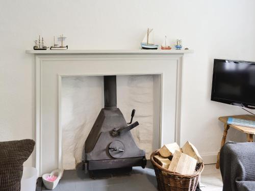 a fireplace with a stove in a living room at Shore Cottage in Carsluith